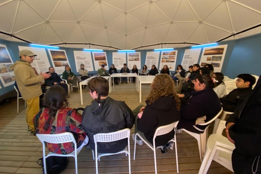 Estudiantes sentados en circulo escuchando instrucciones del académico